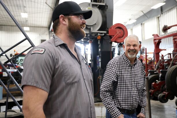 Titan Machinery Technician smiling with a customer in a shop