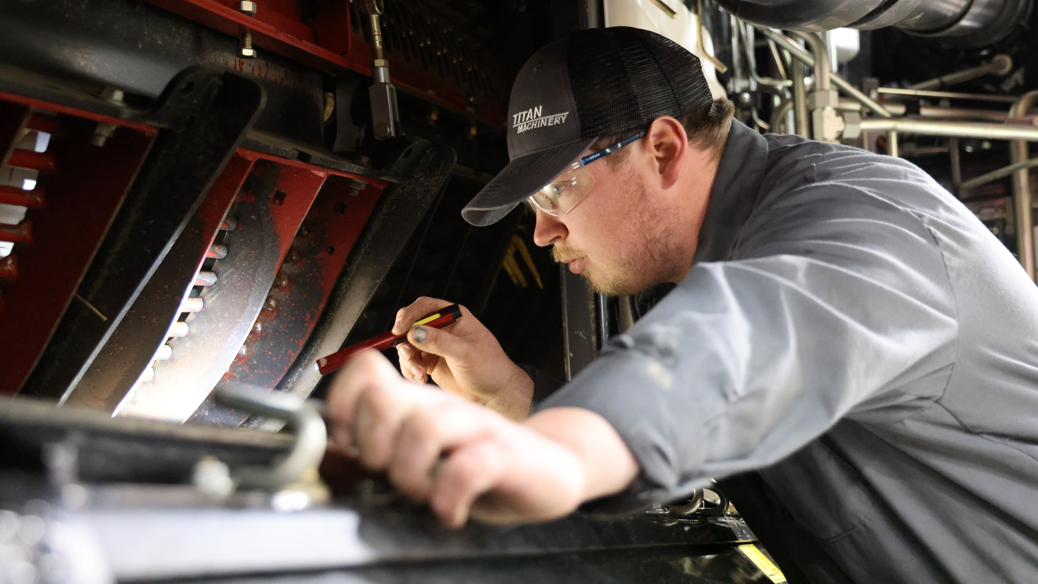 Titan Machinery Technician pointing flashlight into combine