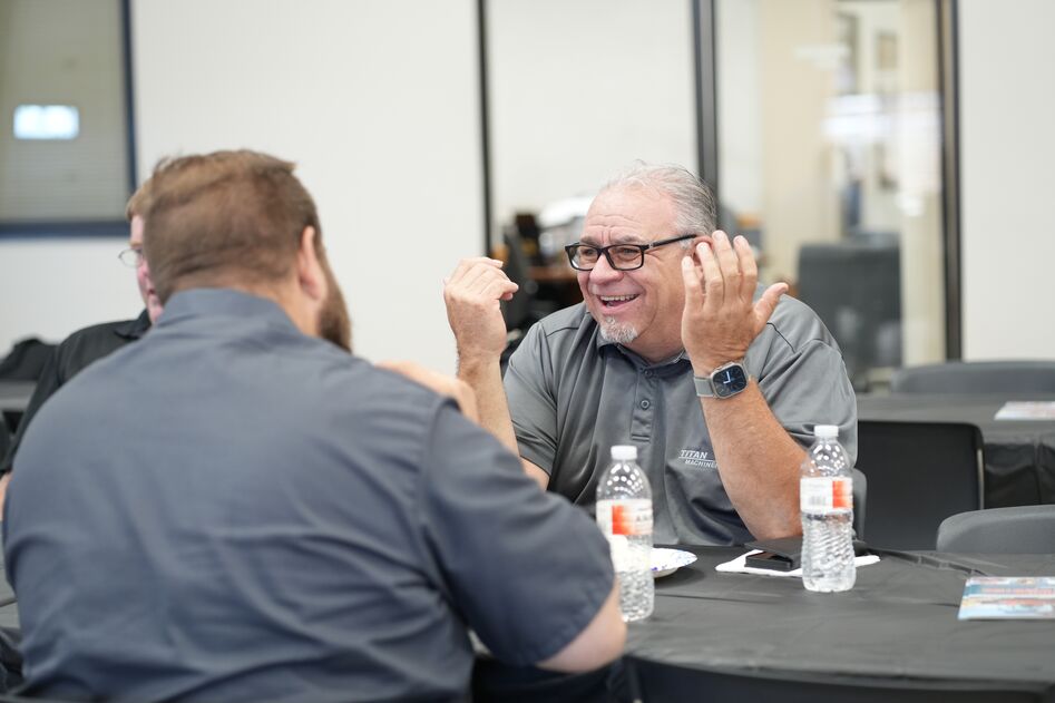 Titan Machinery Equipment Sales Consultant laughing with a customer at a table