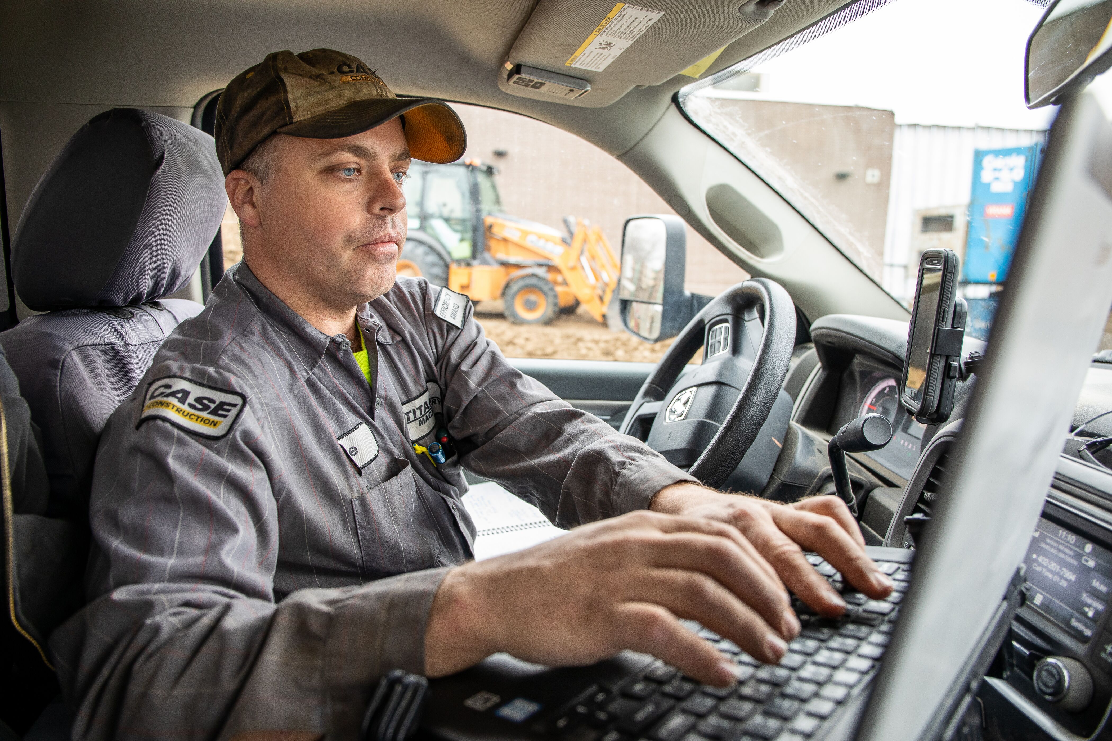 CASE Tech in truck with backhoe in background