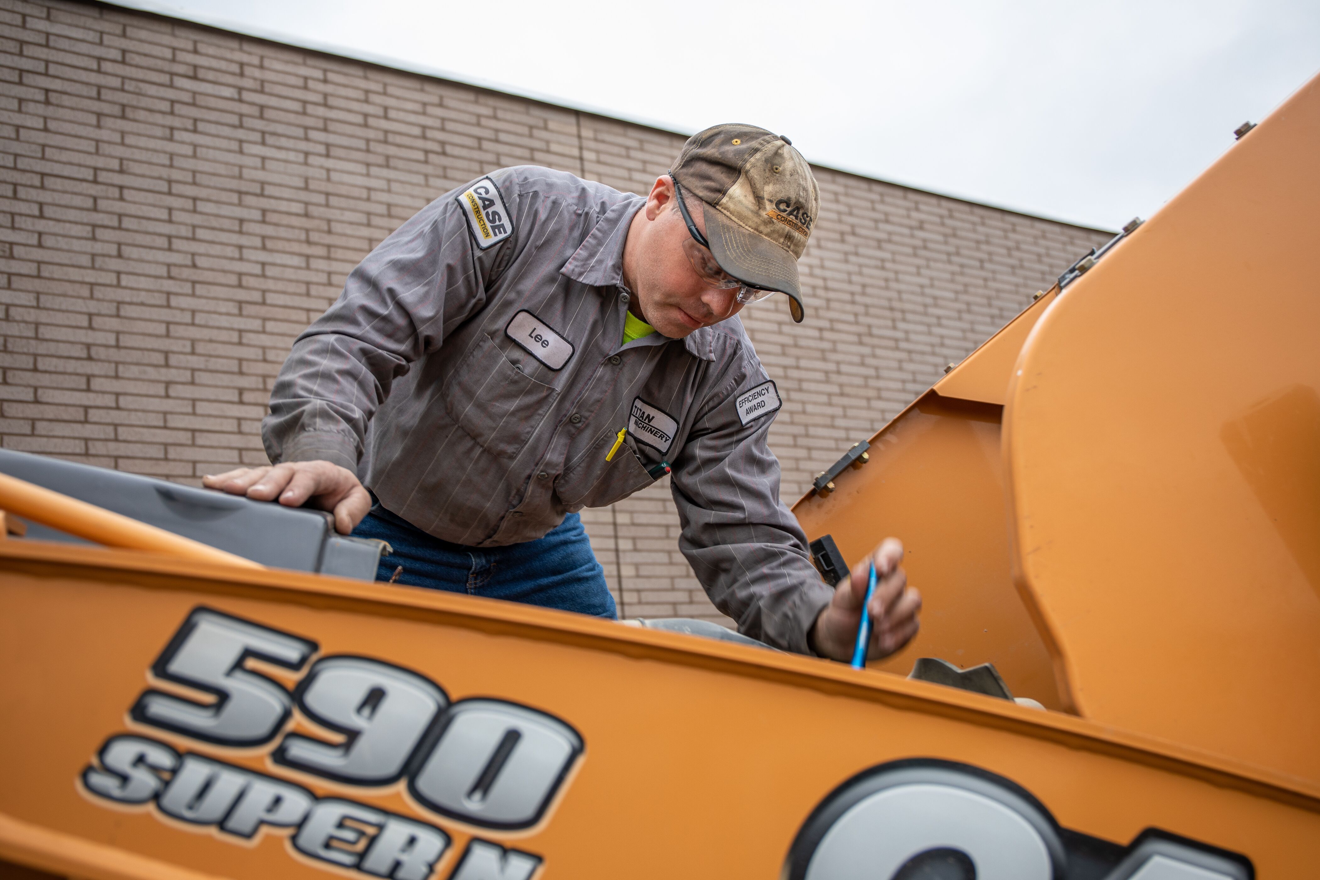 Tech working on CASE backhoe loader